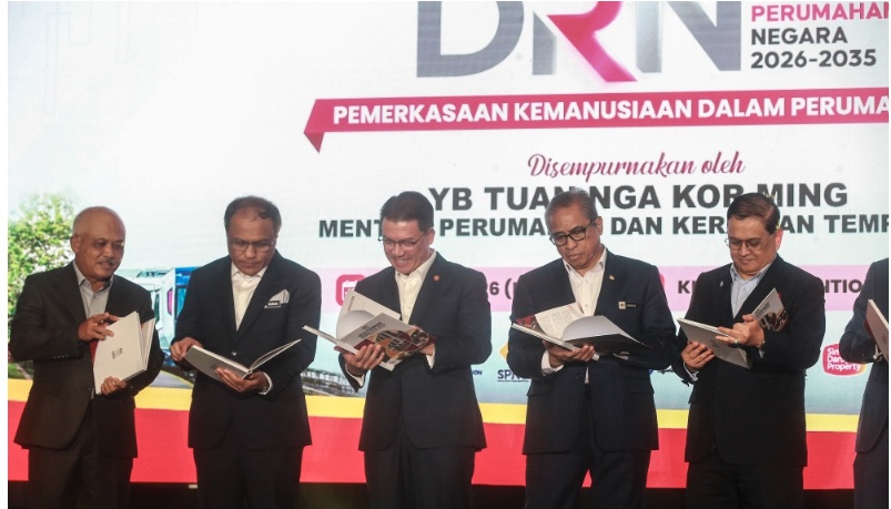 Malaysian government and industry figures at the launch of the Dasar Rumah Negara 2026-2035 national housing policy, each holding an open copy of the policy document