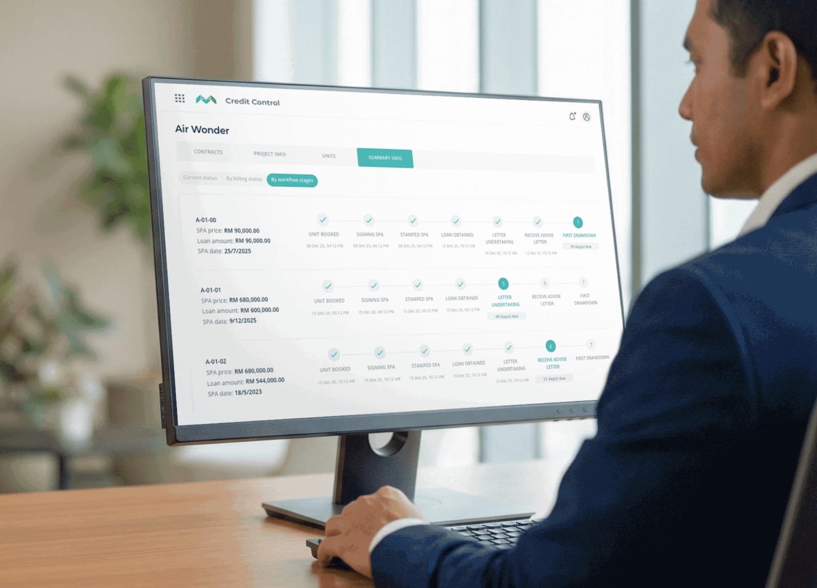 A finance officer at a desktop monitor tracking each unit through its billing stages in MHub Credit Control.
