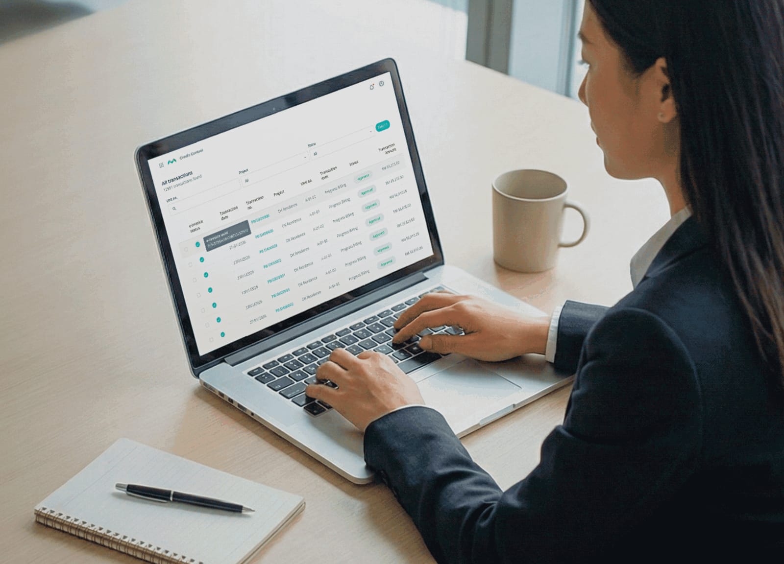 A finance executive on a laptop reviewing a list of billing transactions and their submission status in MHub.